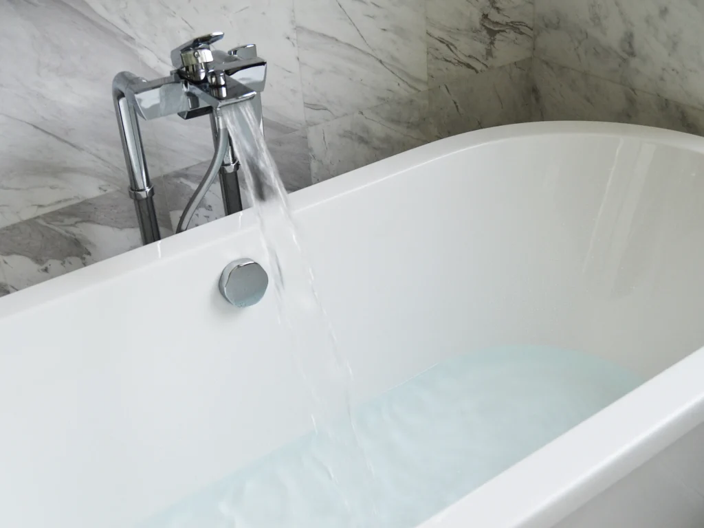 White, clean bathtub and running water faucet